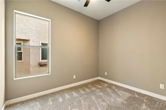 carpeted empty room featuring ceiling fan and baseboards