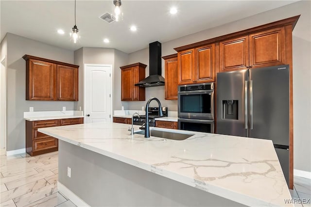 kitchen featuring marble finish floor, visible vents, appliances with stainless steel finishes, brown cabinetry, and wall chimney exhaust hood