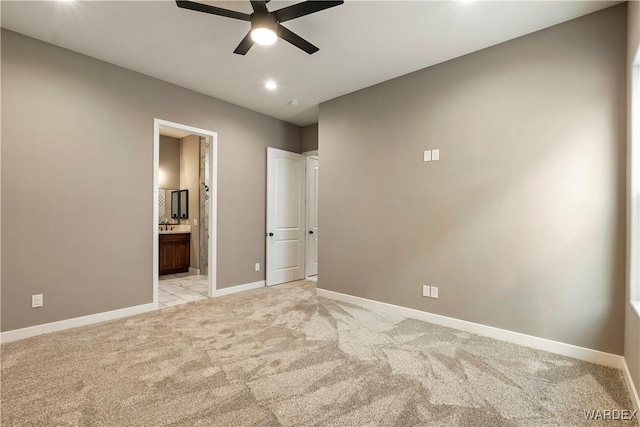 unfurnished bedroom with light carpet, a ceiling fan, baseboards, and connected bathroom