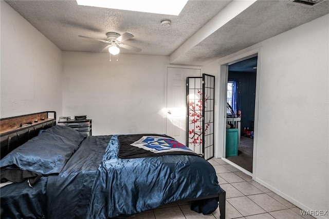 bedroom featuring visible vents, a ceiling fan, light tile patterned flooring, a textured ceiling, and baseboards