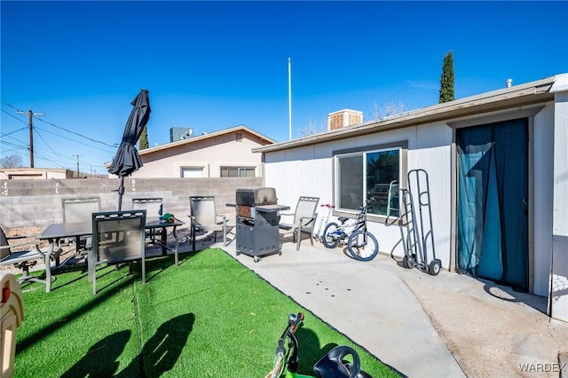 back of house with outdoor dining area, a patio area, fence, and a lawn