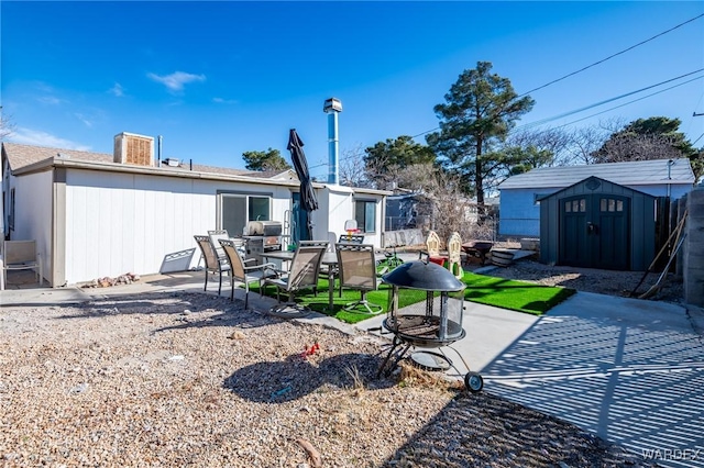 rear view of house with a storage unit, an outdoor fire pit, a patio area, and an outbuilding