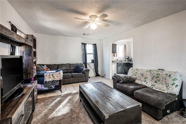 living room featuring ceiling fan, a textured ceiling, light tile patterned flooring, and visible vents