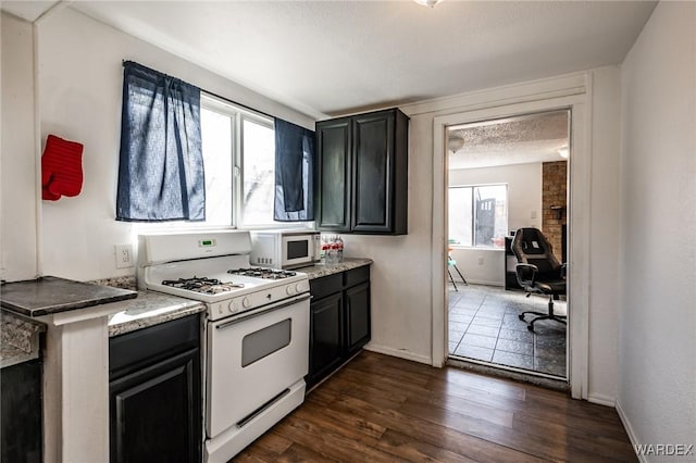 kitchen featuring white appliances, baseboards, dark wood finished floors, and a textured ceiling