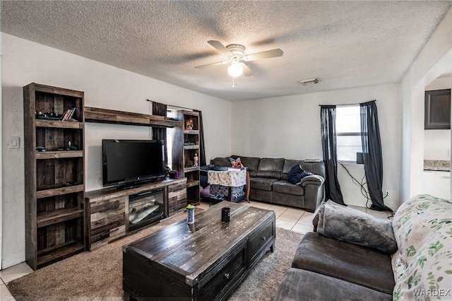 living area featuring visible vents, light tile patterned flooring, ceiling fan, and a textured ceiling