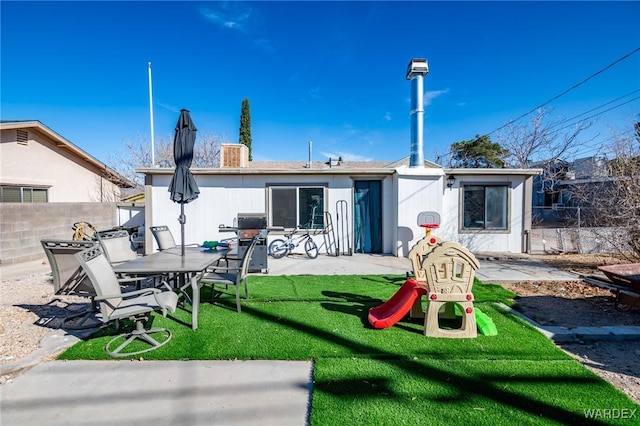 back of house with fence, a patio, and a lawn