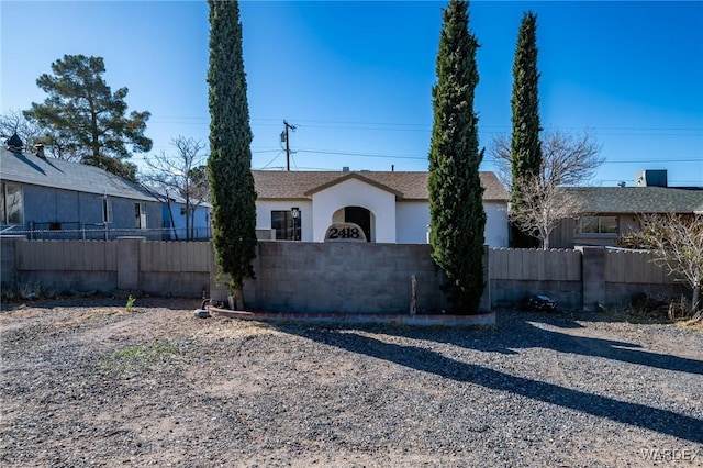 view of front of home with a fenced front yard, a shingled roof, and stucco siding