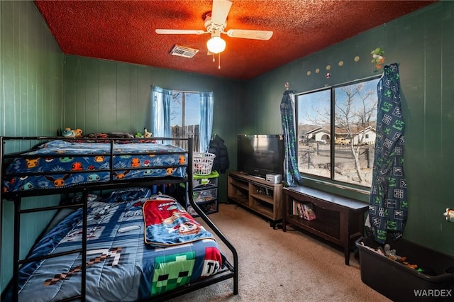 bedroom featuring a ceiling fan, visible vents, a textured ceiling, and carpet flooring