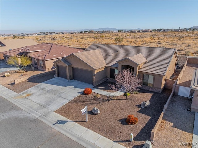 ranch-style house featuring a garage, concrete driveway, a tiled roof, and stucco siding