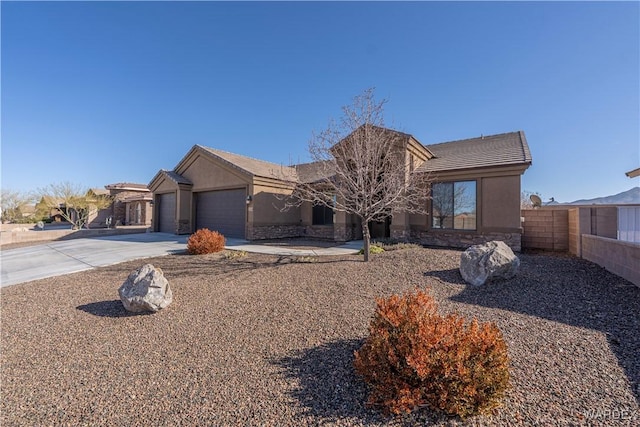 view of front of home with stucco siding, an attached garage, fence, stone siding, and driveway