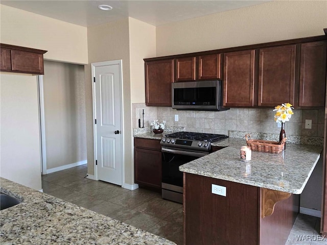 kitchen featuring dark brown cabinets, appliances with stainless steel finishes, backsplash, and light stone counters