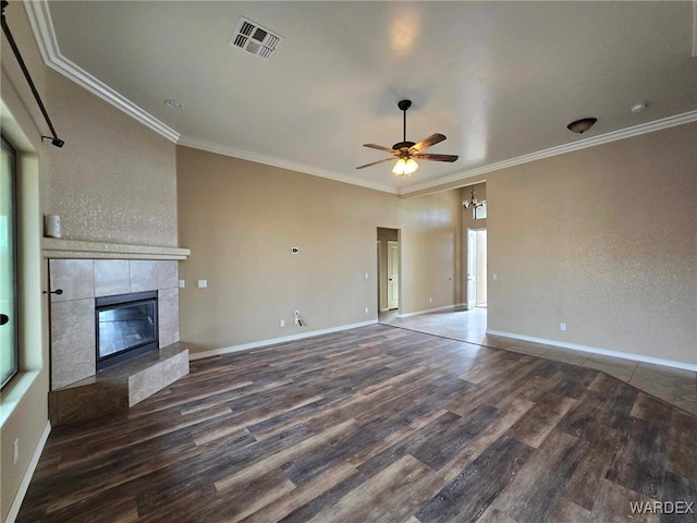 unfurnished living room featuring visible vents, baseboards, ornamental molding, a tiled fireplace, and dark wood finished floors