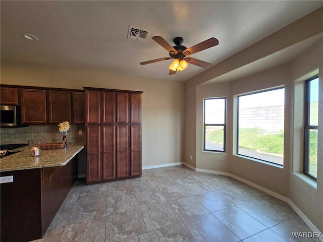 kitchen with light stone counters, visible vents, baseboards, tasteful backsplash, and stainless steel microwave