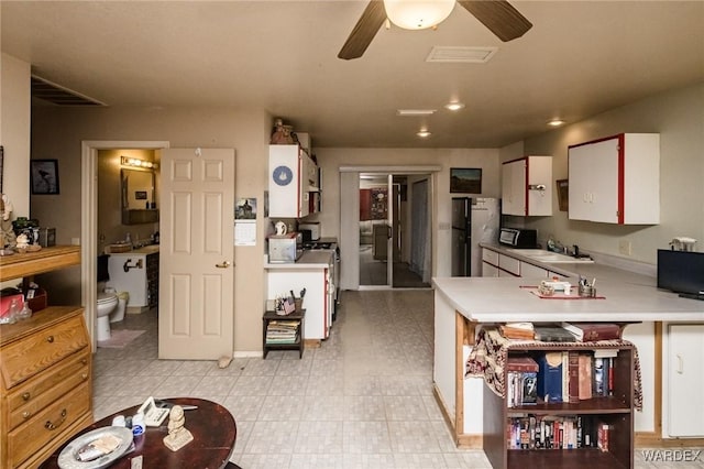 kitchen featuring stainless steel gas range oven, visible vents, white cabinetry, light countertops, and light floors