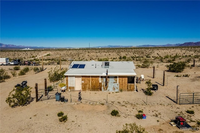 back of property with view of desert, a mountain view, an outdoor structure, and an exterior structure