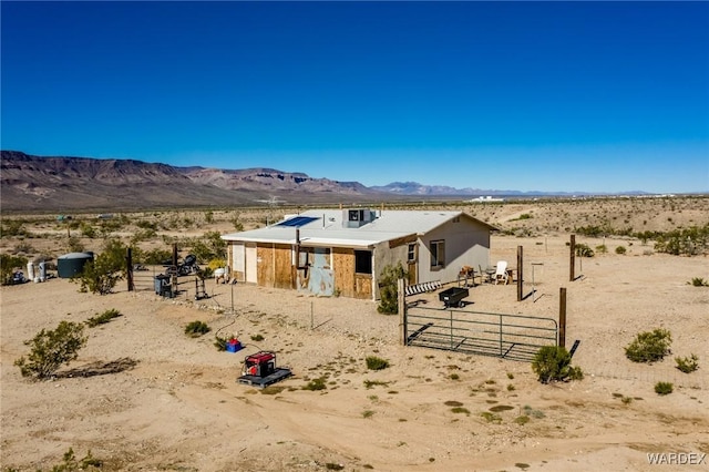 view of front of home with an outbuilding, an exterior structure, a mountain view, and view of desert