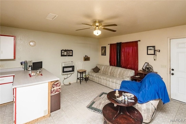 living area with ceiling fan, light floors, visible vents, and heating unit