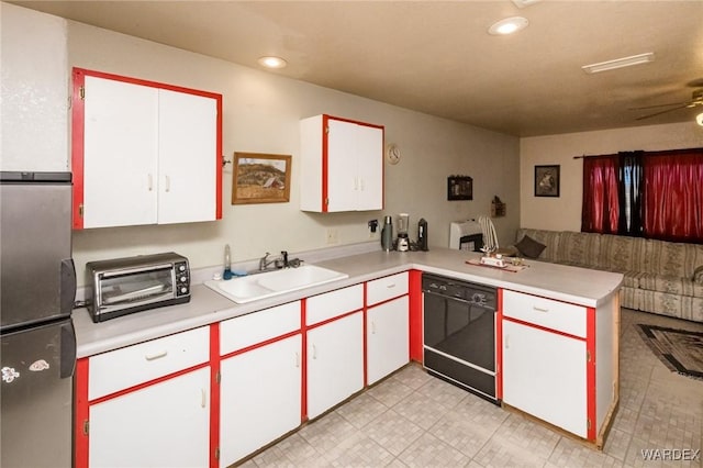 kitchen with black dishwasher, light countertops, freestanding refrigerator, white cabinets, and a peninsula