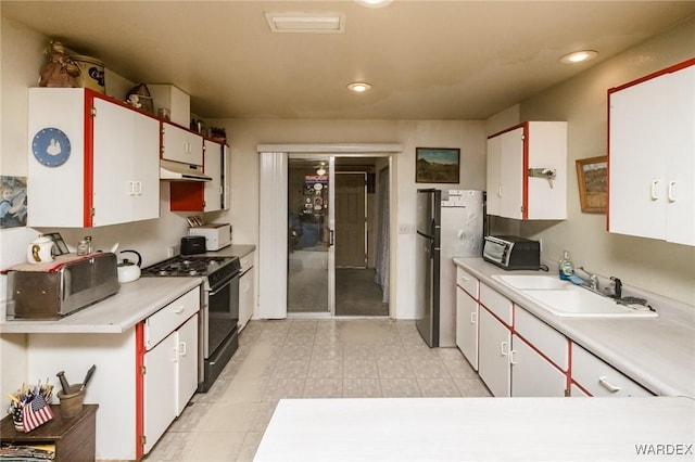 kitchen with white cabinetry, light countertops, a sink, and gas stove