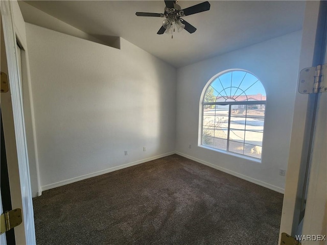 unfurnished room featuring ceiling fan, dark colored carpet, vaulted ceiling, and baseboards