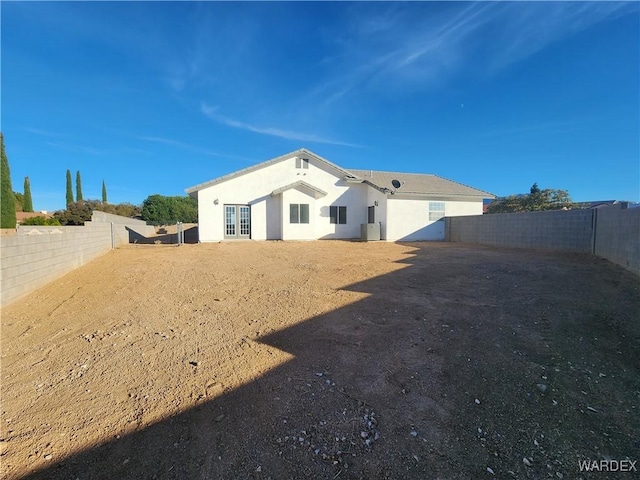 rear view of property featuring a fenced backyard and stucco siding