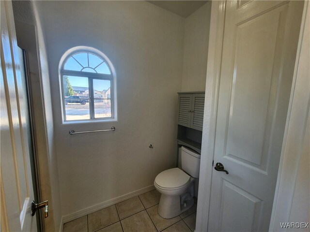 bathroom with toilet, baseboards, and tile patterned floors