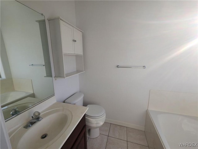 bathroom with toilet, vanity, a tub, baseboards, and tile patterned floors