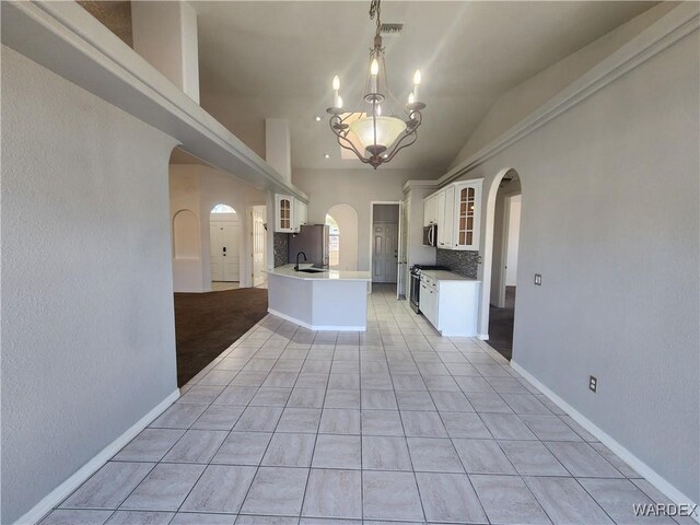 kitchen with white cabinetry, glass insert cabinets, arched walkways, and decorative light fixtures