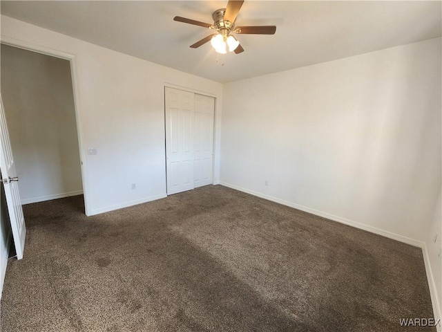 unfurnished bedroom with a ceiling fan, dark colored carpet, a closet, and baseboards