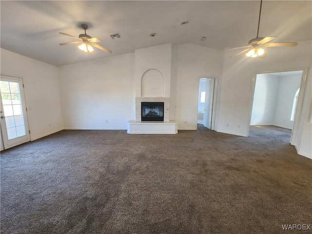 unfurnished living room with a ceiling fan, visible vents, dark carpet, and a tiled fireplace