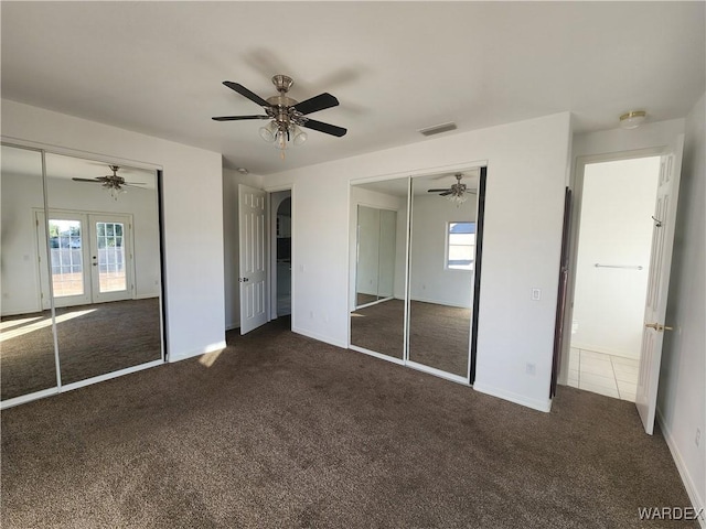 unfurnished bedroom with visible vents, multiple windows, dark carpet, and french doors