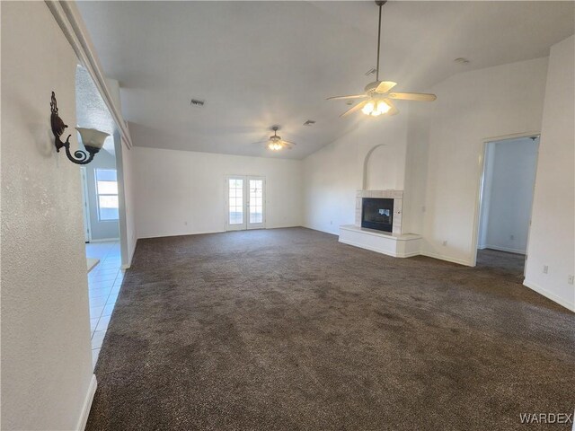 unfurnished living room with dark tile patterned flooring, lofted ceiling, dark carpet, ceiling fan, and a tile fireplace