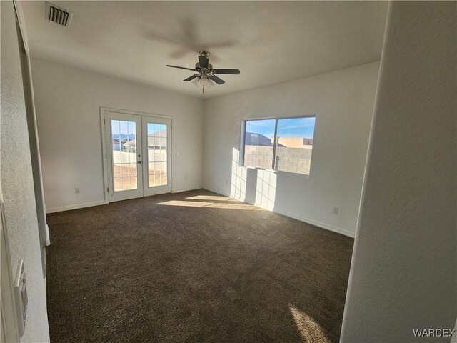 empty room with dark colored carpet, plenty of natural light, and visible vents