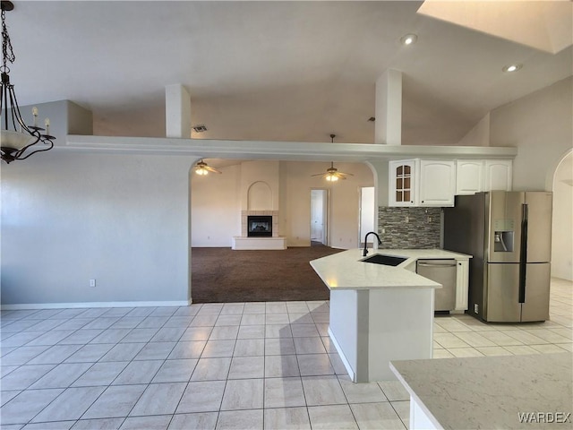 kitchen with glass insert cabinets, a sink, white cabinets, appliances with stainless steel finishes, and decorative light fixtures