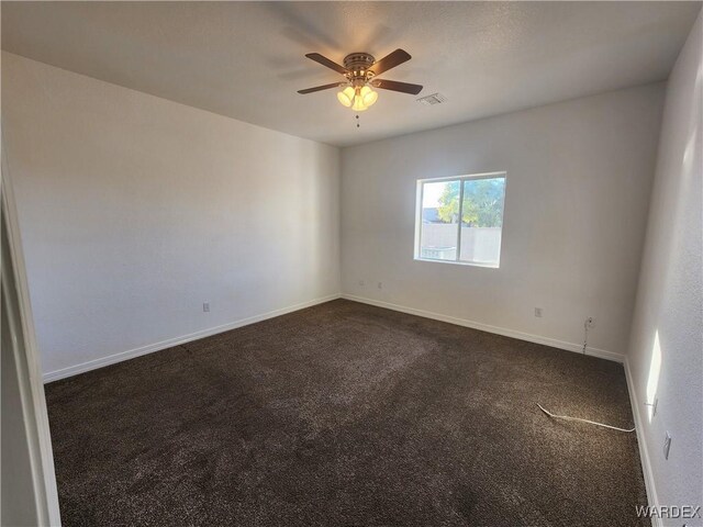 empty room with dark colored carpet, visible vents, ceiling fan, and baseboards