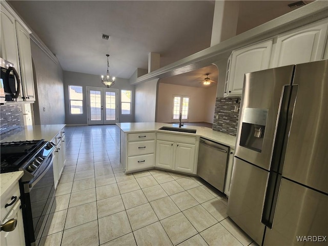 kitchen featuring french doors, stainless steel appliances, tasteful backsplash, open floor plan, and a sink