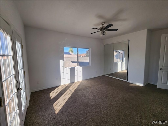 empty room featuring dark carpet, a ceiling fan, and baseboards