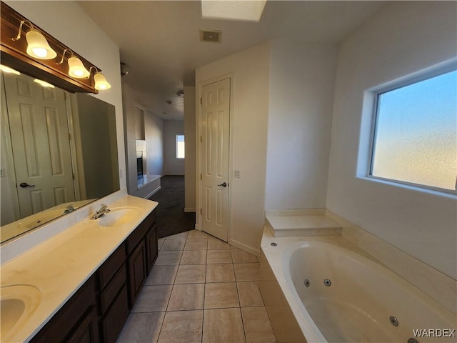 bathroom with double vanity, visible vents, a sink, tile patterned flooring, and a tub with jets