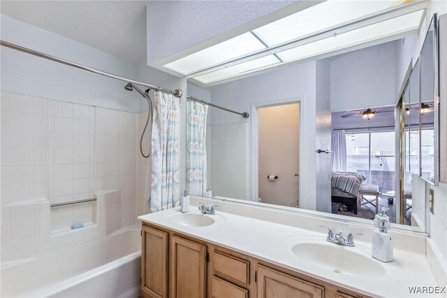 bathroom with double vanity, ceiling fan, shower / bath combo with shower curtain, and a sink