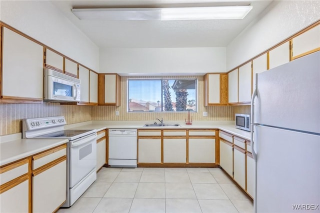 kitchen with white appliances, light tile patterned floors, light countertops, white cabinetry, and a sink