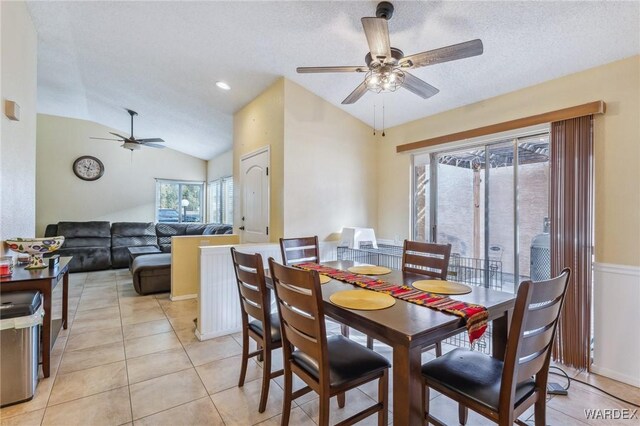 dining area featuring lofted ceiling, light tile patterned floors, a textured ceiling, and a ceiling fan