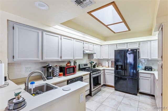 kitchen with light countertops, white cabinets, a sink, under cabinet range hood, and black appliances