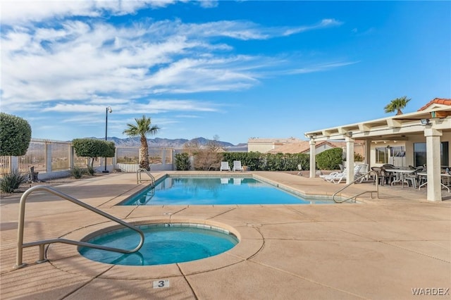 pool featuring a patio, fence, a mountain view, and a hot tub