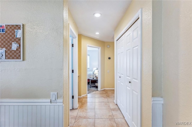 hall with wainscoting and light tile patterned flooring