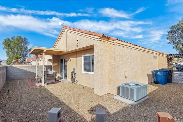 back of house featuring a fenced backyard, a tiled roof, cooling unit, and stucco siding