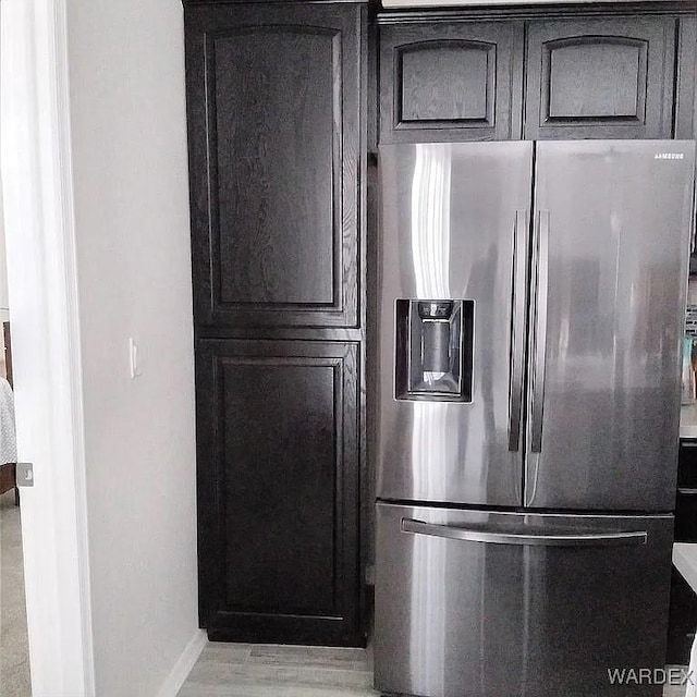 kitchen with dark brown cabinetry, light wood finished floors, baseboards, light countertops, and stainless steel refrigerator with ice dispenser