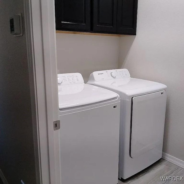 laundry area with independent washer and dryer, cabinet space, and baseboards