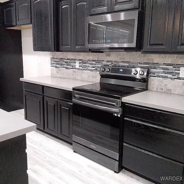 kitchen featuring appliances with stainless steel finishes, light countertops, light wood-style flooring, and decorative backsplash