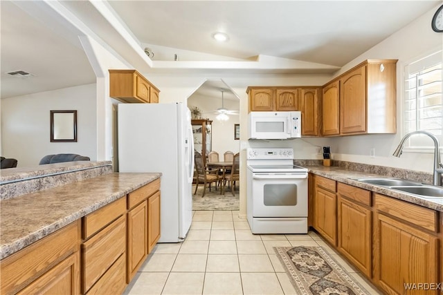 kitchen featuring visible vents, brown cabinetry, a sink, vaulted ceiling, and white appliances