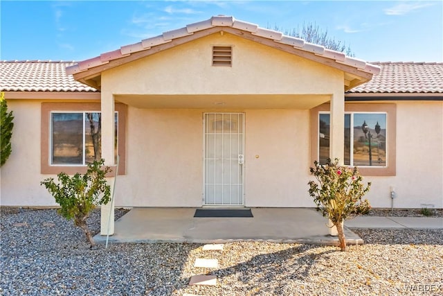 exterior space featuring a patio area, a tiled roof, and stucco siding